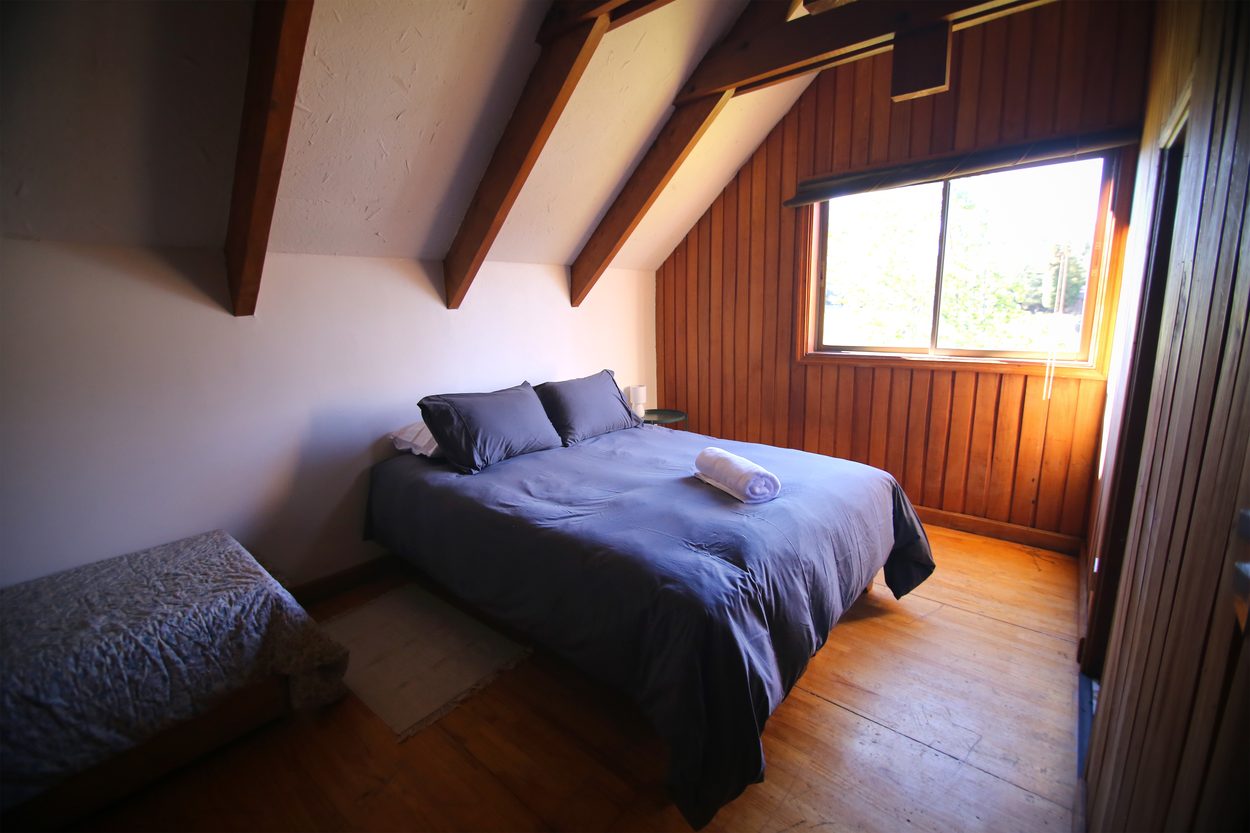 Cama matrimonial y cama chica bajo las vigas del segundo piso